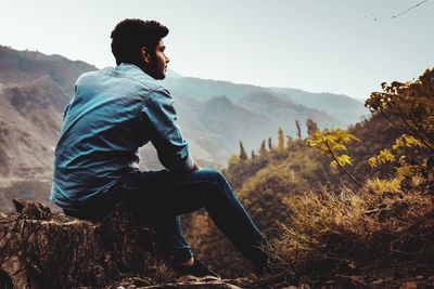 Full length of young man sitting on mountain