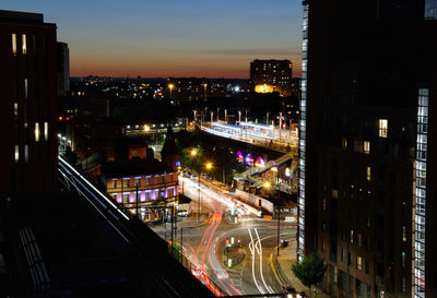 High angle view of illuminated street amidst buildings in city at night