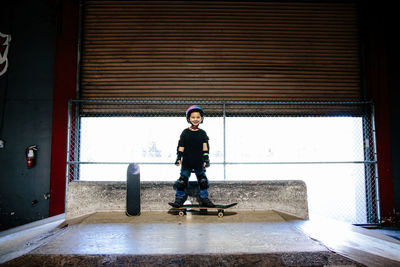 Young boy stands on a skateboard and smiles for the camera