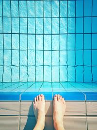 Low section of woman standing by swimming pool