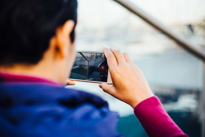 Rear view of man photographing through mobile phone