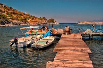 Boats moored on pier by sea against clear sky