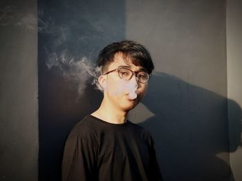 Portrait of young man looking away against wall