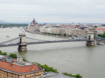 Bridge over river in city against sky