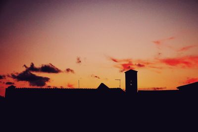Low angle view of silhouette factory against sky during sunset