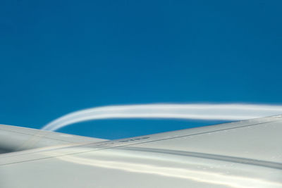 Airplane wing against clear blue sky
