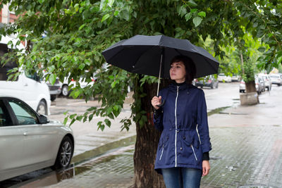 An adult woman with an umbrella walks down the street peering into people's faces  cloudy rainy day.