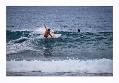 Low section of man surfing in sea