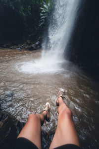 Low section of woman by waterfall