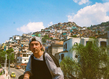 Portrait of young man standing against favela vidigal in rio de janeiro 