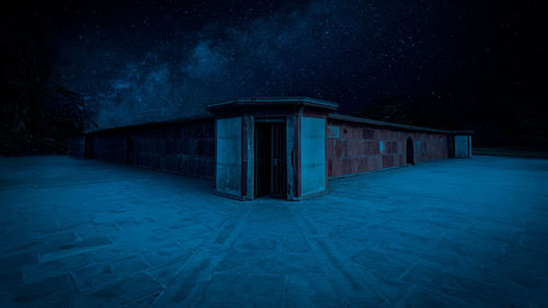 Empty footpath by building against sky at night