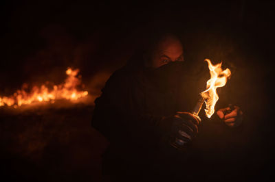 Cropped image of man holding fire at night