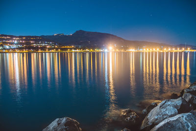 Scenic view of illuminated sea against sky at night