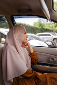 Side view of woman wearing hijab sitting in car