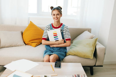 Portrait of young woman using laptop while sitting on bed at home