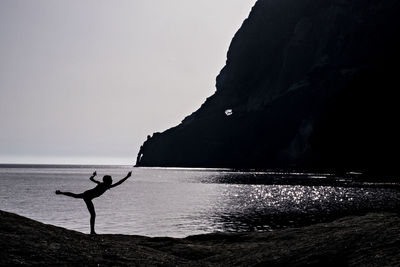 Silhouette girl at beach against clear sky