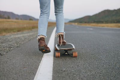 Low section of woman skateboarding on road