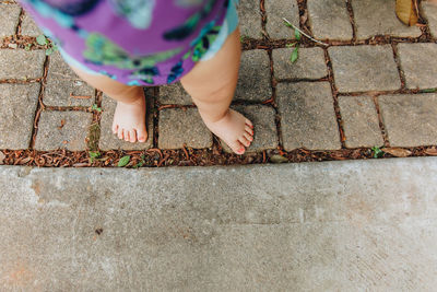 Low section of girl standing on cobblestone