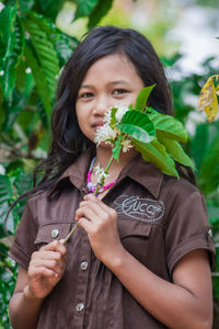 Portrait of a beautiful young woman holding plant