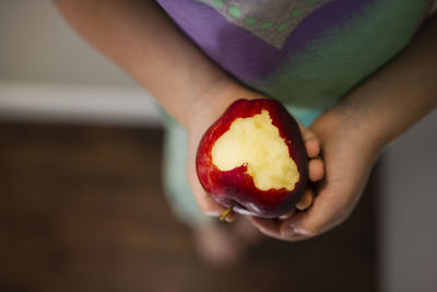 Low section of girl holding eaten apple at home