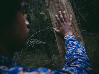 Midsection of woman with tree trunk in forest