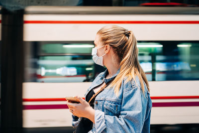 Side view of woman standing against train