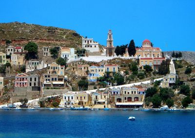 Buildings at waterfront against blue sky