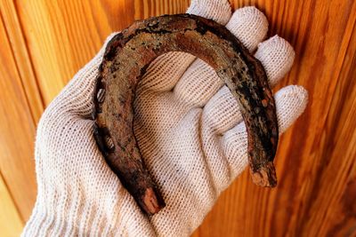 Cropped hand holding old horseshoe on wooden table