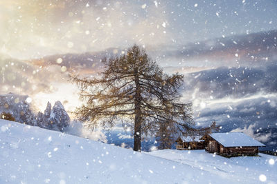 Cottages on snowcapped mountain against cloudy sky