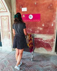 Rear view of woman standing against wall