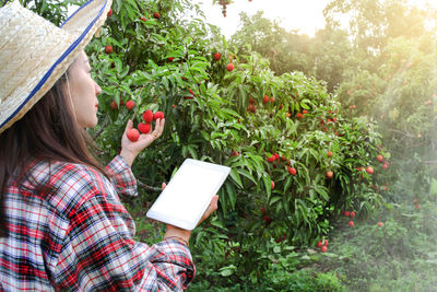 Side view of woman holding fresh fruit plants