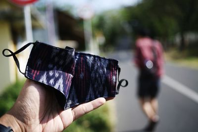 Close-up of hand holding mobile phone outdoors