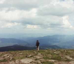 Rear view of man on mountain against cloudy sky