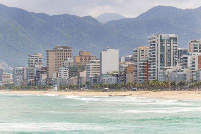 City by sea and mountains against sky