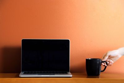 Close-up of man using laptop on table