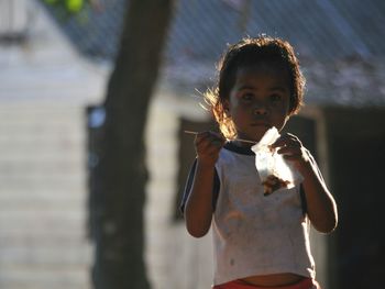 Girl eating food while standing outdoors