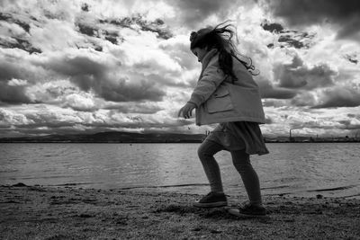 Woman standing at beach against sky