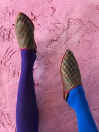 Low section of woman standing on pink wall