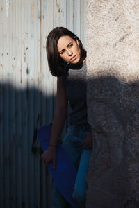 Thoughtful young woman holding skateboard outdoors