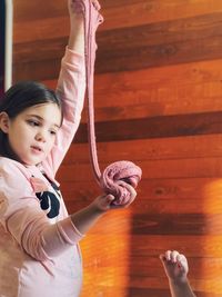 Little girl playing with large gum for hands standing against wooden wardrobe