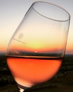 Close-up of beer in glass against sunset sky