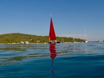 Sailboat in sea against clear blue sky