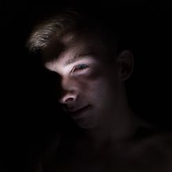 Close-up portrait of young man against black background