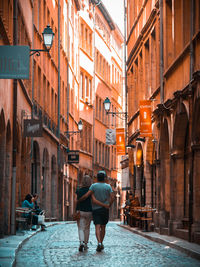 Rear view of people walking on street amidst buildings