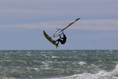 Man surfing in sea against sky