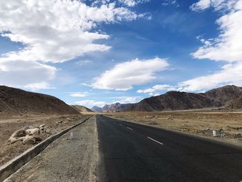 Road leading towards mountains against sky