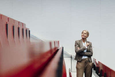 Businesswoman contemplating by red auditorium seats