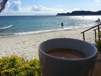 Close-up of drink on beach against sky