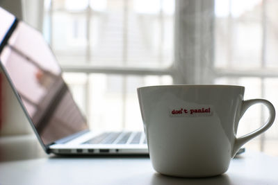 Dont panic text on cup by laptop at home