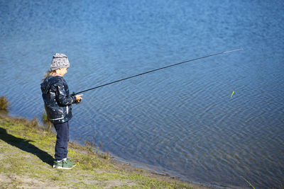 Six year old girl fishing on the autumn lake with a fishing rod